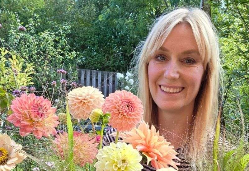 Женщина держит в руках большой яркий букет свежесрезанных цветов